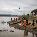 Equipe de resgate em ação próxima à margem de um rio em Lavrinhas