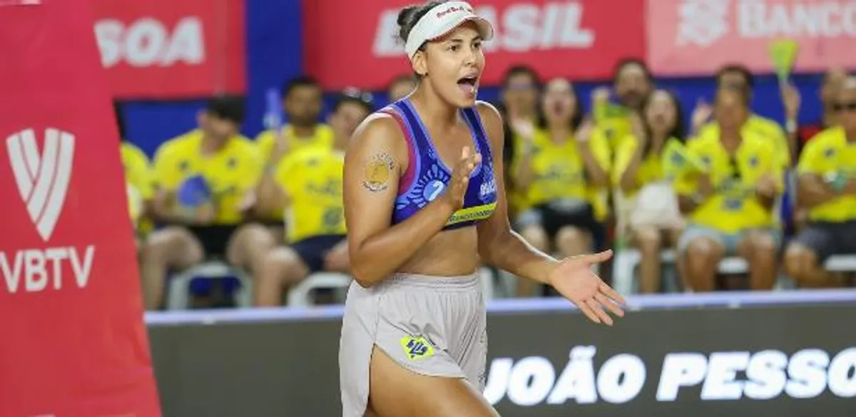Duplas brasileiras competindo em uma partida de vôlei de praia com o público ao fundo.