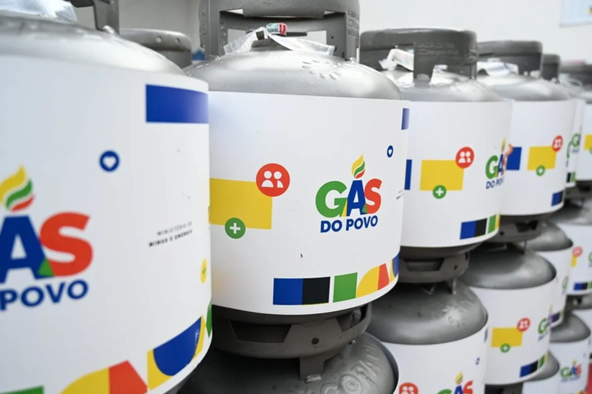 Mulher recebendo botijão de gás do programa Gás do Povo.