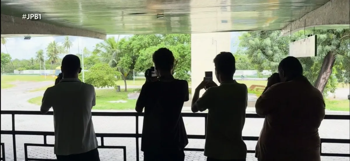 Jovens busólogos observam ônibus em João Pessoa com interesse técnico.