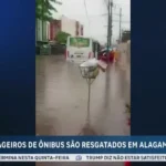 Rua alagada em João Pessoa com ônibus ilhado e equipes de resgate chegando de bote