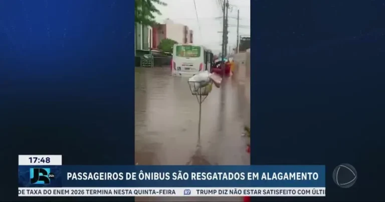 Rua alagada em João Pessoa com ônibus ilhado e equipes de resgate chegando de bote
