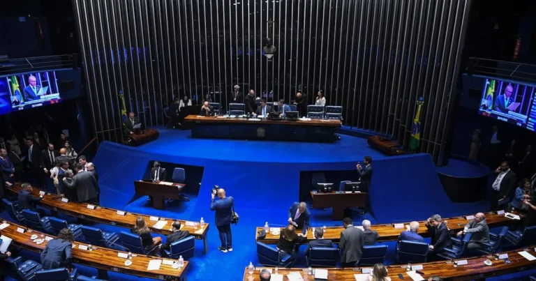 Senadores em corredor do Senado Federal, discutindo planos políticos para as eleições de 2026, com alguns visando governos estaduais e outros a reeleição.