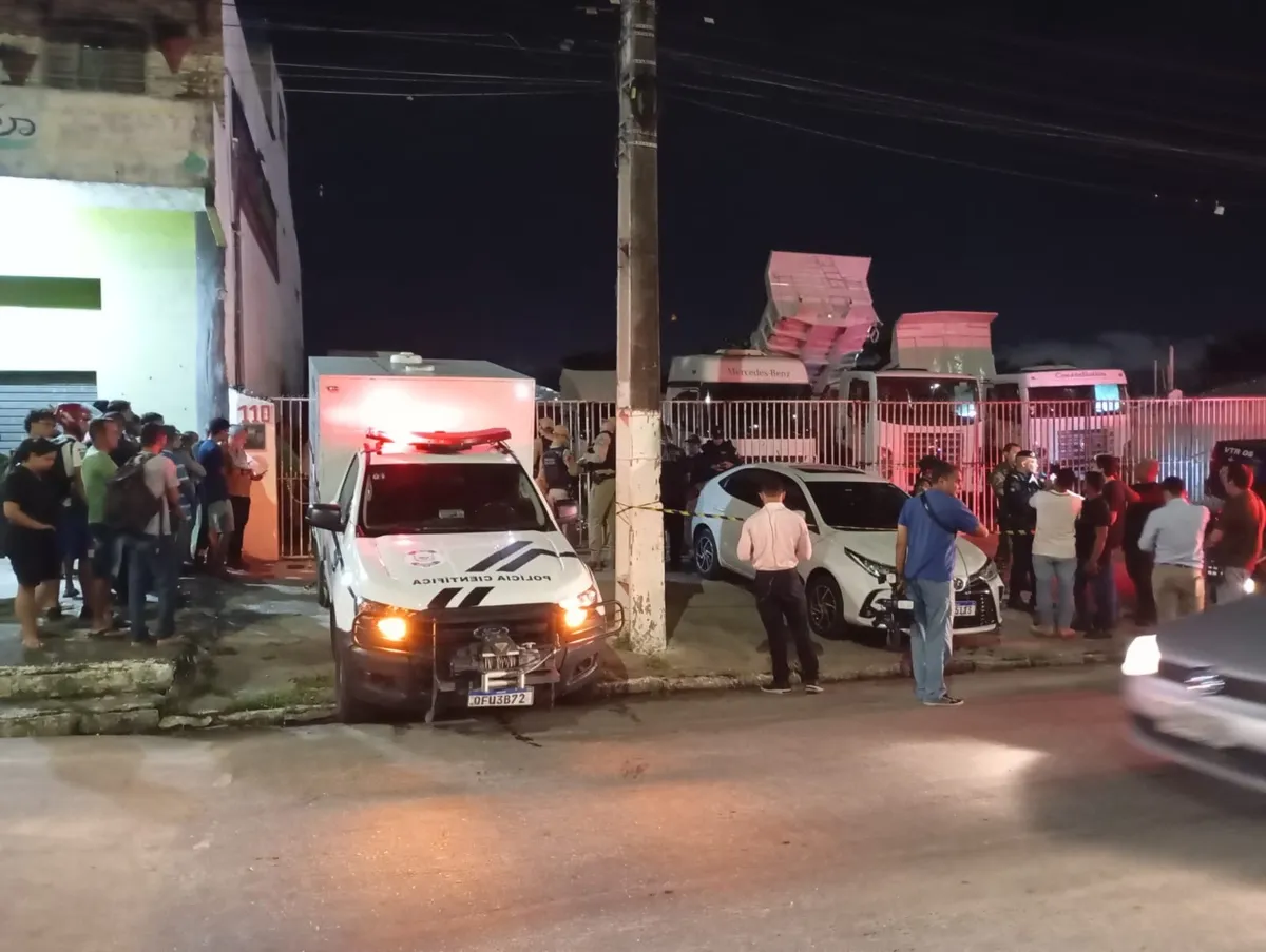 Fachada de concessionária de carros em Bayeux, local de assassinato de empresário, com viatura policial ao fundo