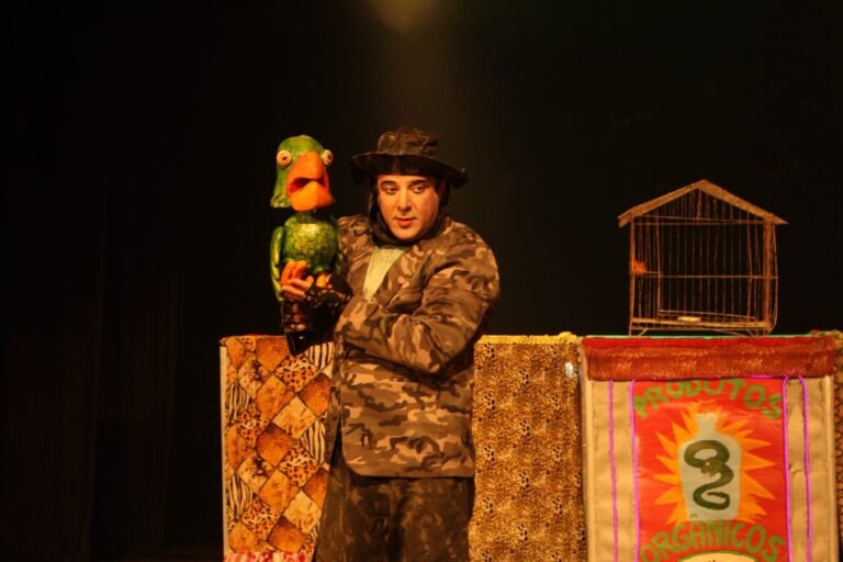 Atores em performance teatral em festival nacional com público diverso assistindo em praça pública