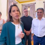 Governadora Raquel Lyra sorrindo em evento junino, com adereços típicos de São João ao fundo