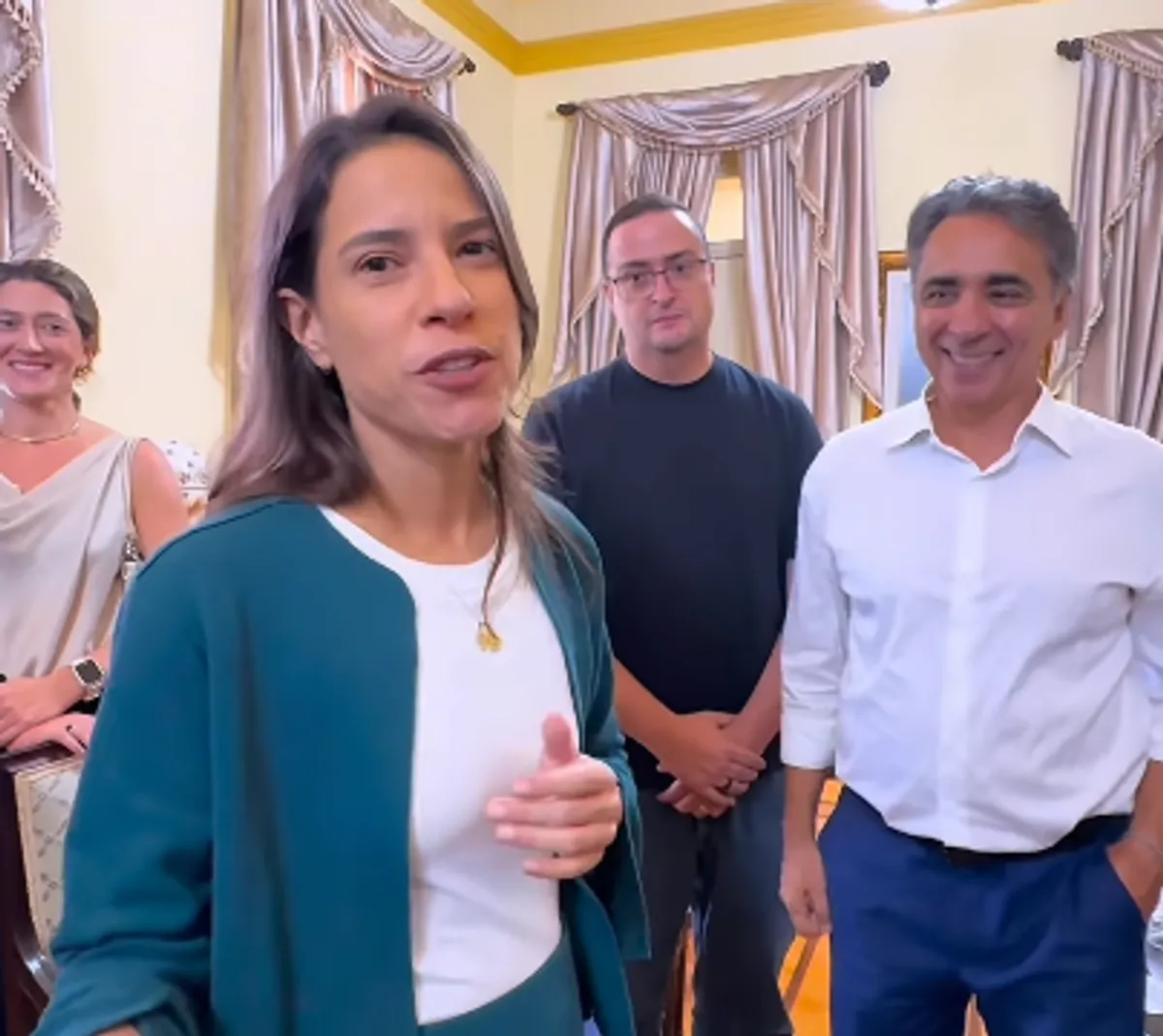 Governadora Raquel Lyra sorrindo em evento junino, com adereços típicos de São João ao fundo