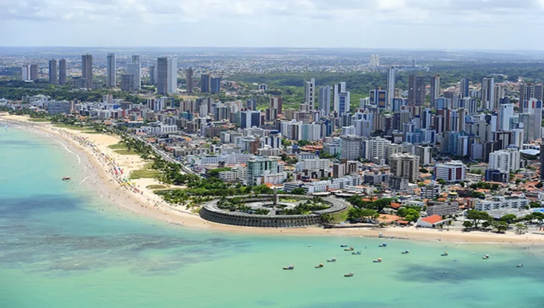Empreendimento imobiliário moderno em João Pessoa com vista para o mar ao pôr do sol.