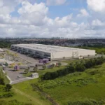 Centro de distribuição logístico em João Pessoa com caminhões e atividades de carga/descarga.