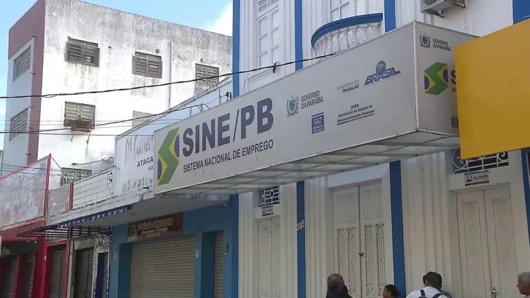 Candidatos em um escritório do Sine na Paraíba, preenchendo formulários e conversando com atendentes em busca de vagas de emprego.