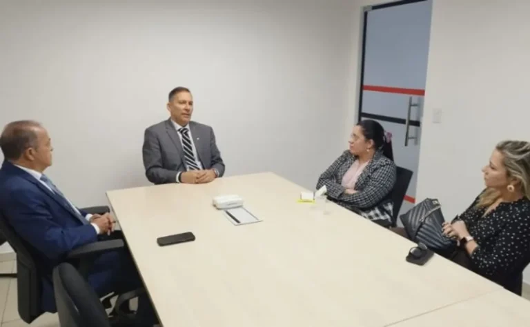 Dois homens em trajes formais, representando o Ministério Público e a Secretaria de Administração Penitenciária, apertando as mãos em um escritório, simbolizando colaboração.