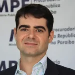 Mãos organizando documentos do MP Eleitoral para as Eleições de 2026 na Paraíba
