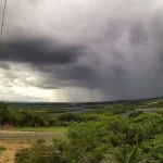 Chuvas intensas em rua de João Pessoa, com carros e pessoas sob forte precipitação, refletindo o alerta do Inmet.