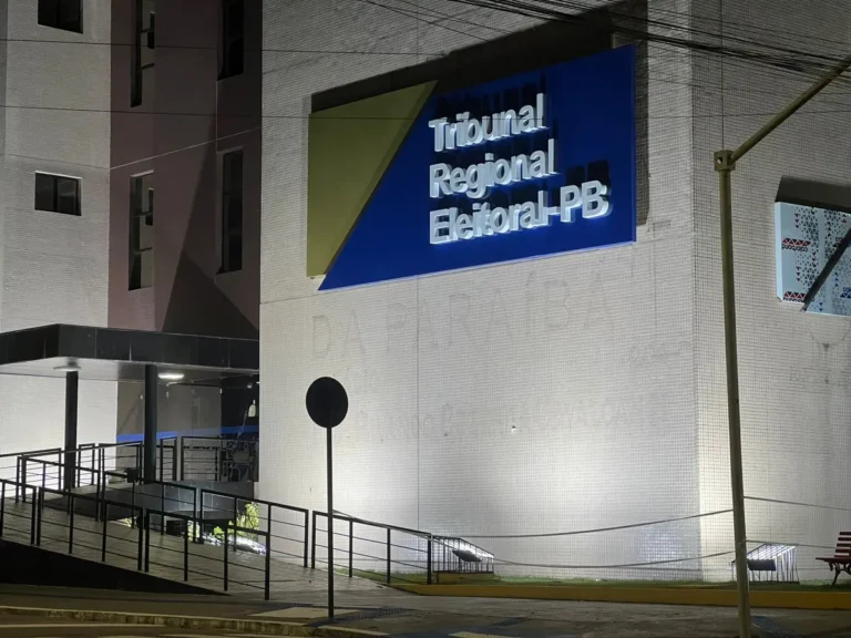 Painel de monitoramento de eleições exibido em tela grande em sala de reunião.