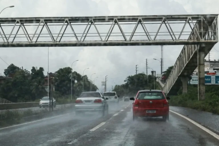 Rua em João Pessoa sob forte chuva e ventos intensos com galhos de árvores caindo e pessoas buscando abrigo.