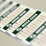 Duas mãos seguram bilhetes da Mega-Sena premiados.