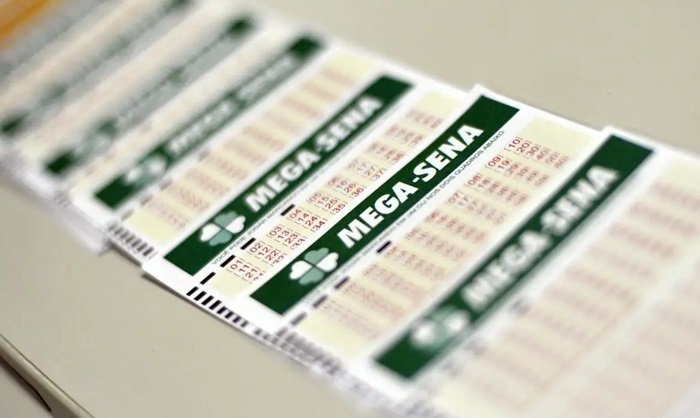 Duas mãos seguram bilhetes da Mega-Sena premiados.