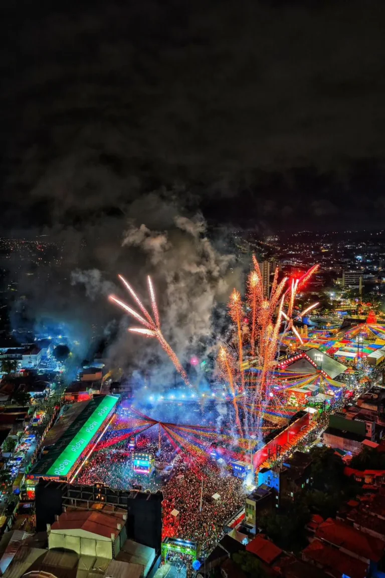 Vista aérea noturna do Parque do Povo em Campina Grande durante as festividades do São João, com milhares de pessoas reunidas.