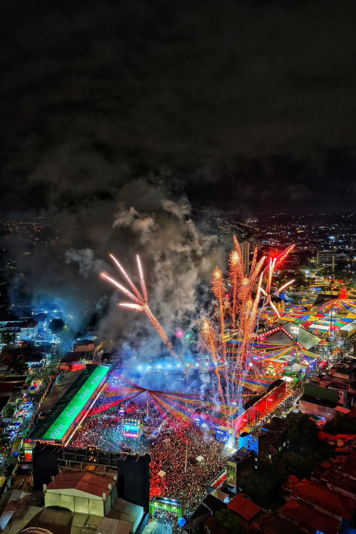 Vista aérea noturna do Parque do Povo em Campina Grande durante as festividades do São João, com milhares de pessoas reunidas.