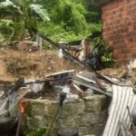 Rua alagada em cidade nordestina após fortes chuvas, com moradores observando o estrago.