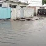 Rua de João Pessoa alagada sob chuva intensa com pessoas e carros em dificuldade