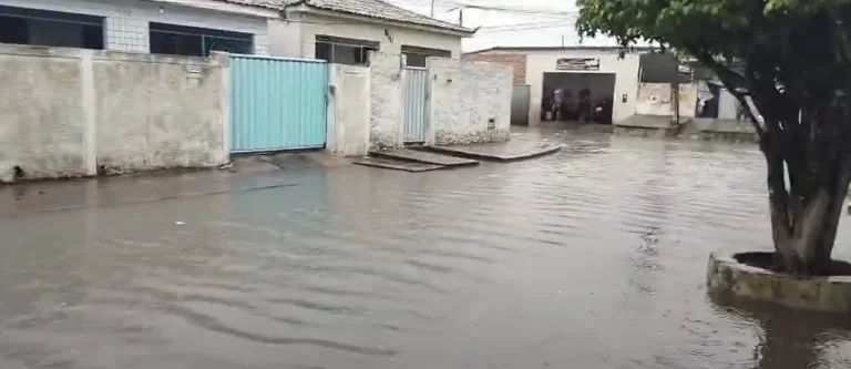 Rua de João Pessoa alagada sob chuva intensa com pessoas e carros em dificuldade
