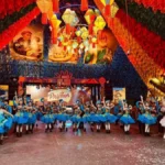 Pessoas dançando quadrilha com bandeirinhas e fogueira em uma festa junina vibrante na Paraíba