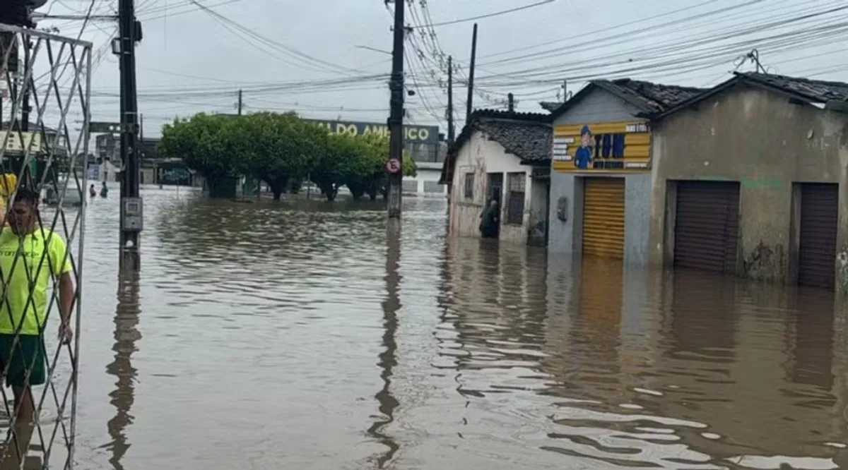 Ruas de João Pessoa inundadas após fortes chuvas, com carros parcialmente submersos.