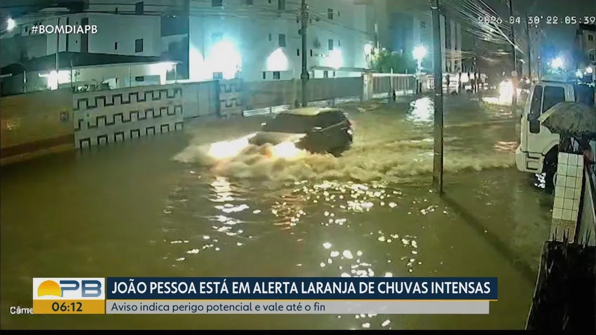 Rua alagada em João Pessoa devido a chuvas intensas, com carros parcialmente submersos.
