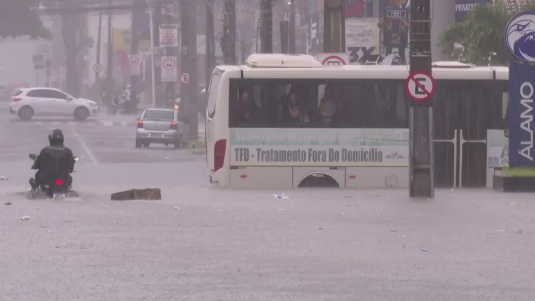 Rua alagada em João Pessoa com pessoas enfrentando fortes chuvas