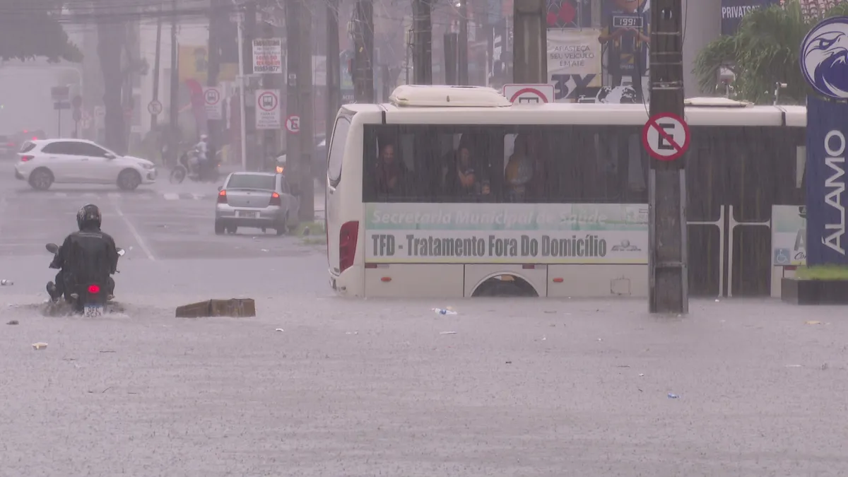 Rua alagada em João Pessoa com pessoas enfrentando fortes chuvas