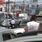 Trânsito intenso em uma avenida de João Pessoa com muitos veículos parados.