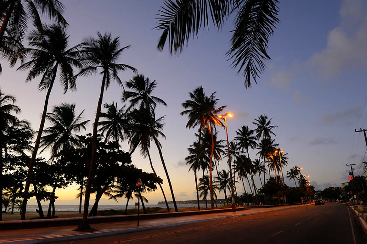 Skyline moderno de João Pessoa com praia e mar ao fundo, simbolizando o crescimento turístico e imobiliário.