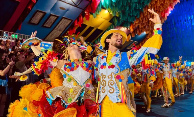 Multidão celebrando em uma festa de São João no Nordeste do Brasil com fogos de artifício e shows no palco.
