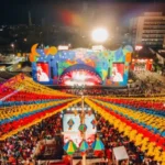 Vista aérea vibrante do São João em Campina Grande, Paraíba, com muitas pessoas dançando e decorações coloridas iluminando a noite