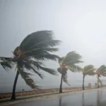 Rua em João Pessoa com chuva intensa e céu nublado.