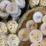 Mesa com diversas comidas típicas de festa junina em João Pessoa, com destaque para pamonha e pastéis.