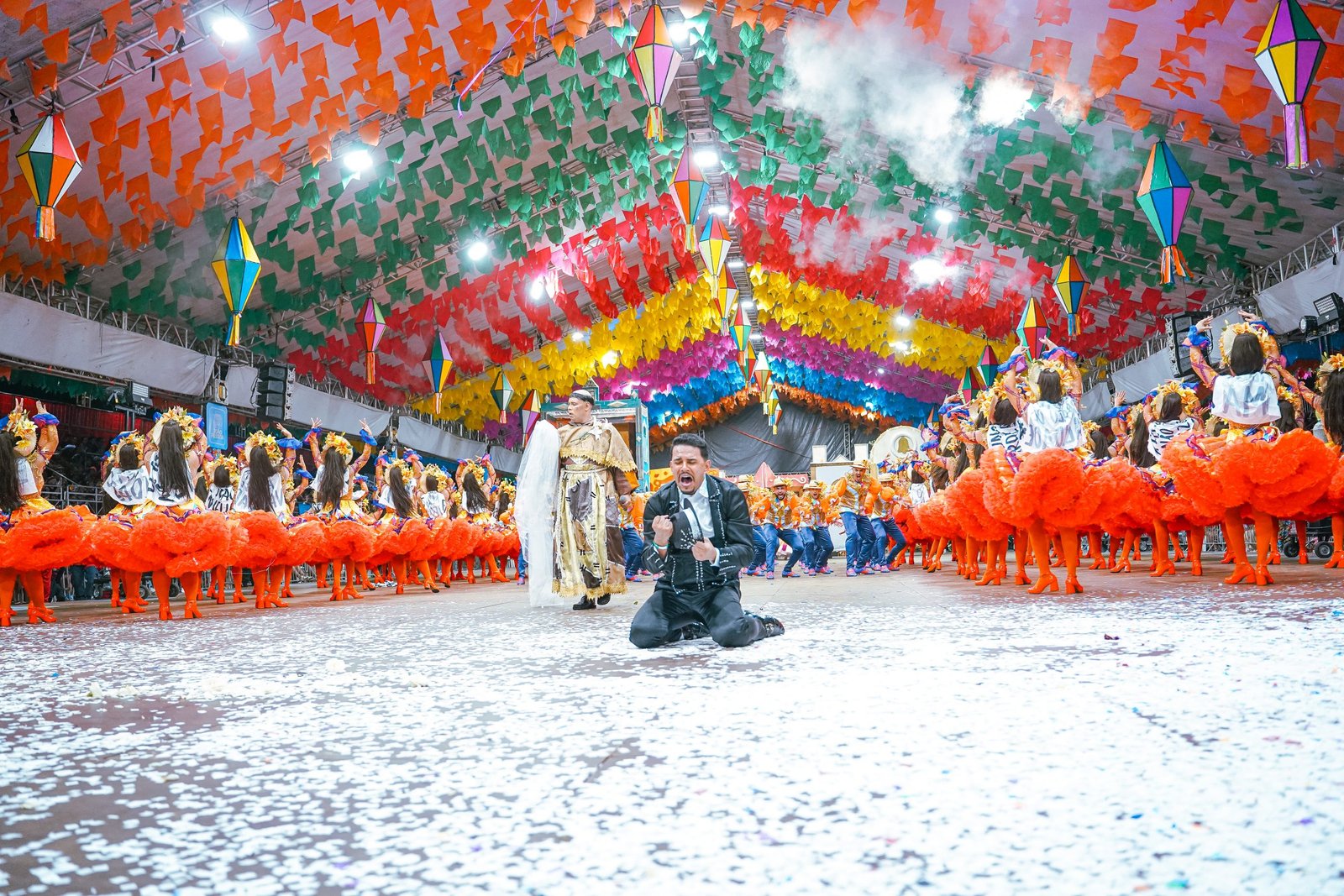Apresentação vibrante de quadrilha junina durante o Paraíba Junino, com dançarinos em trajes coloridos e público animado.