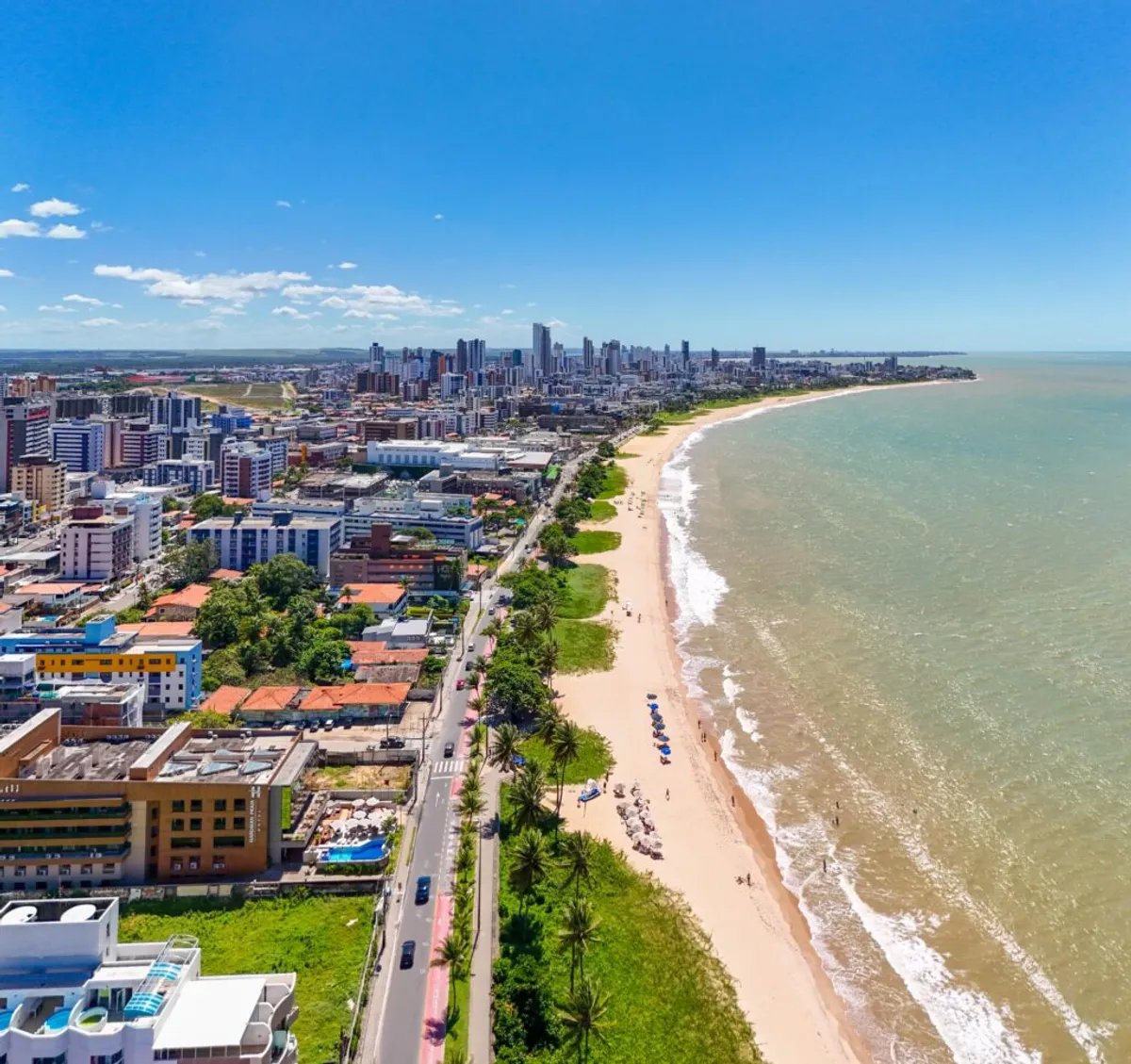 Centro urbano de João Pessoa com edifícios modernos e o mar ao fundo, simbolizando crescimento econômico.