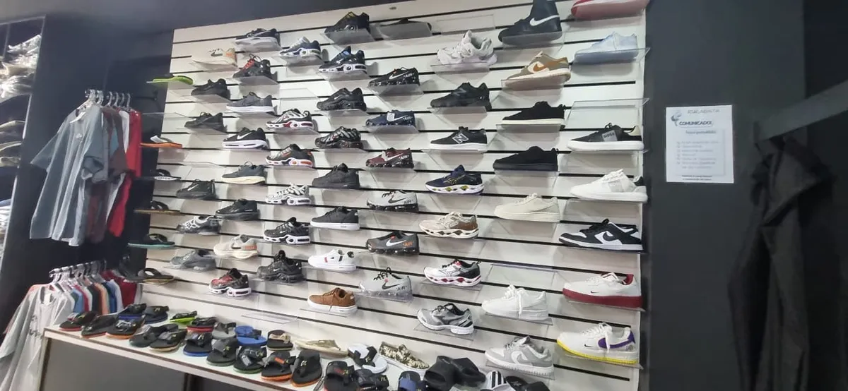 Grande quantidade de roupas, tênis e bonés falsificados apreendidos em operação policial.