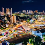 Pessoas dançando e celebrando em uma vibrante festa de São João na Paraíba com palco iluminado e bandeirinhas.