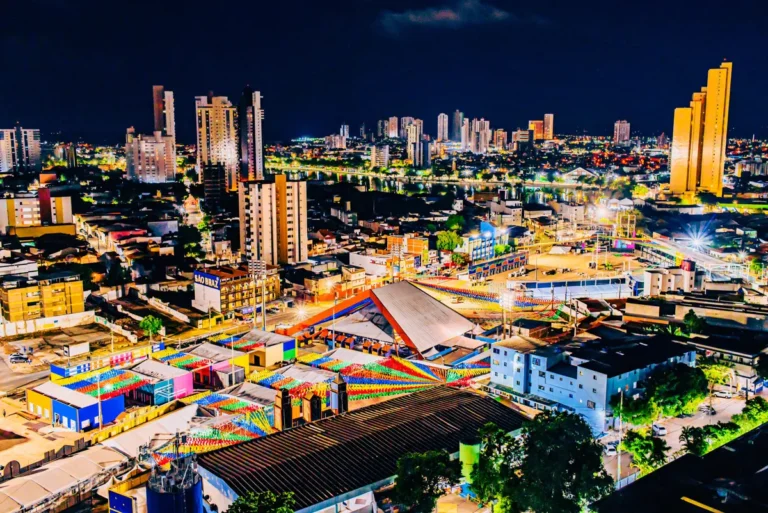 Pessoas dançando e celebrando em uma vibrante festa de São João na Paraíba com palco iluminado e bandeirinhas.