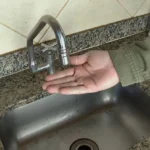 Torneira seca e balde vazio em uma casa, simbolizando a suspensão do abastecimento de água em Campina Grande pela Cagepa.