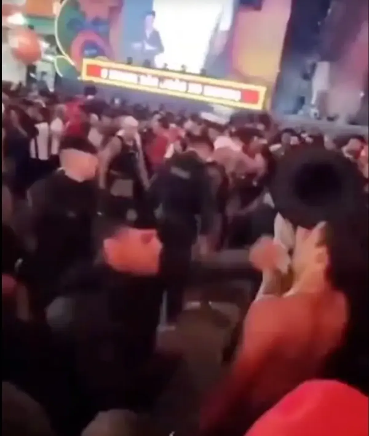 Policial militar em evento público noturno, com expressão séria.