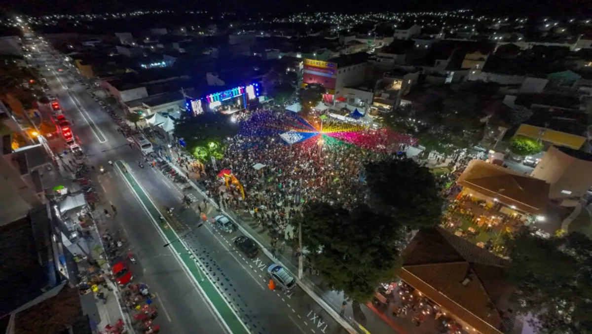 Multidão celebra em frente a um palco iluminado durante o São João de Sumé 2026, com banda de forró tocando e decorações juninas visíveis.