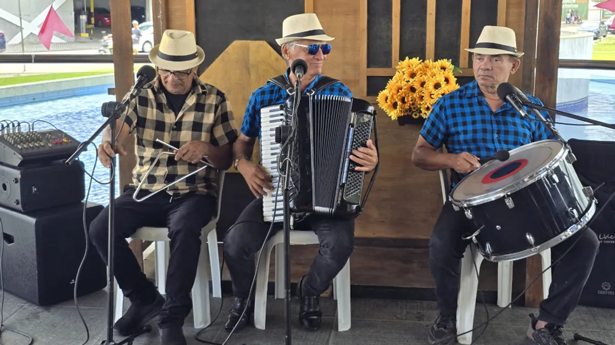 Trio de forró se apresentando na entrada do SESI Museu Digital durante celebrações juninas.