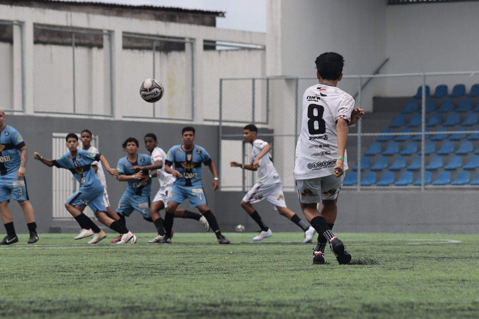 Jogo de futebol da Taça das Favelas Paraíba 2026 em João Pessoa com jovens atletas em campo.