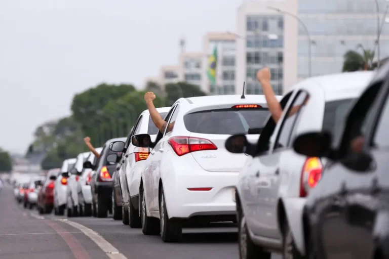 Fiscal eleitoral aponta para adesivo de propaganda em carro de aplicativo, indicando irregularidade.