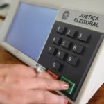 Gráfico em sala de imprensa na Paraíba mostrando queda de 42% em candidaturas para eleições de 2026 comparado a 2022.