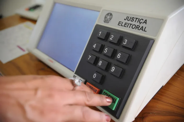 Gráfico em sala de imprensa na Paraíba mostrando queda de 42% em candidaturas para eleições de 2026 comparado a 2022.